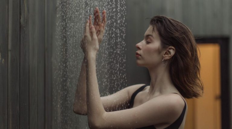 Femme en maillot de bain prenant une douche extérieure